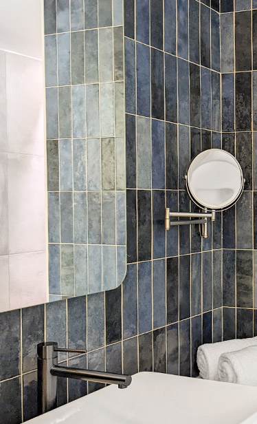 Beautiful blue taled bathroom with a mirror and a sink, from the hotel Maison Juste