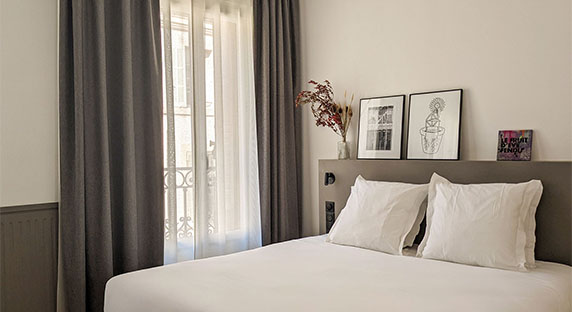 Modern, spacious and bright hotel room with white linen and grey curtains